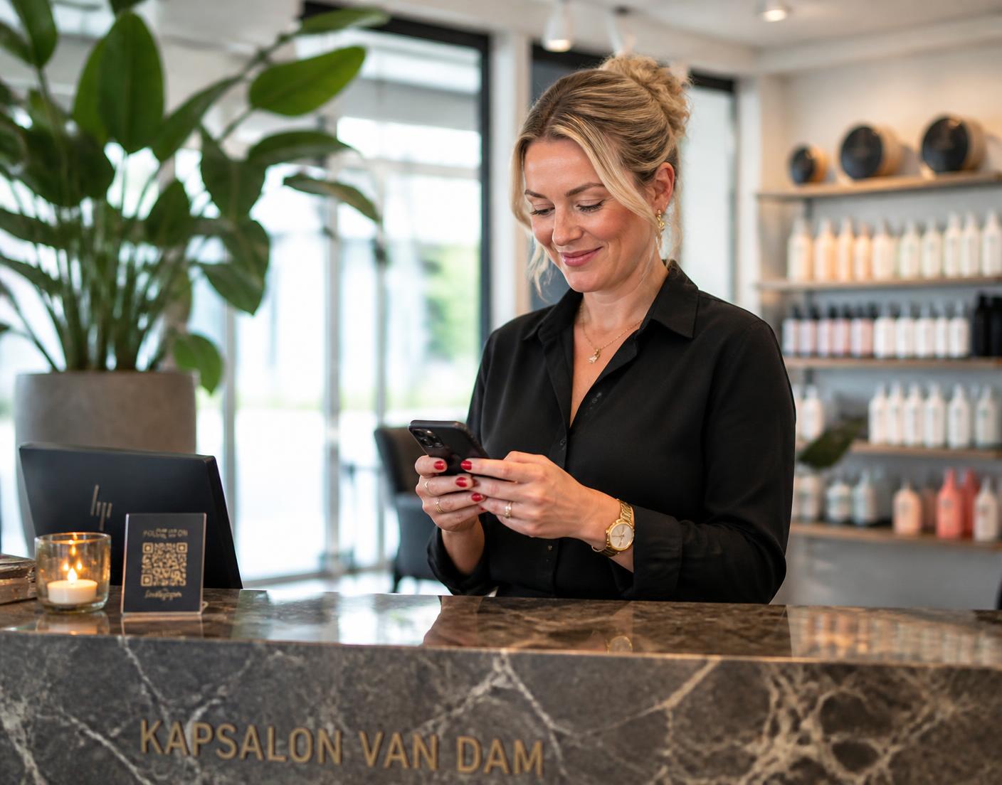 Saloneigenaresse kijkt op haar telefoon bij de balie